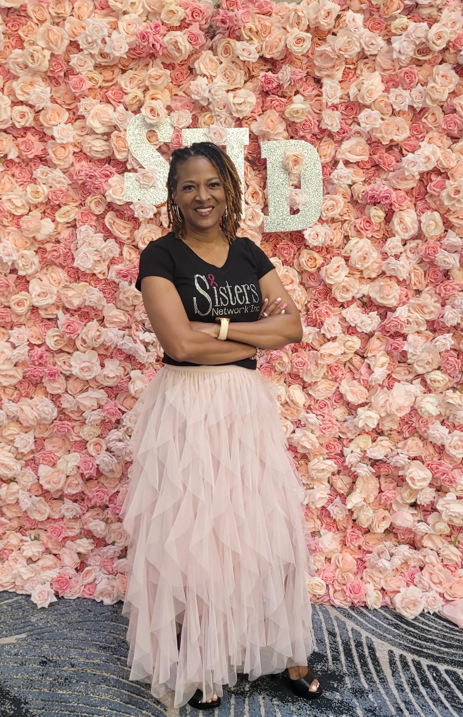 LaWanda Crawford standing before a wall of pink flowers